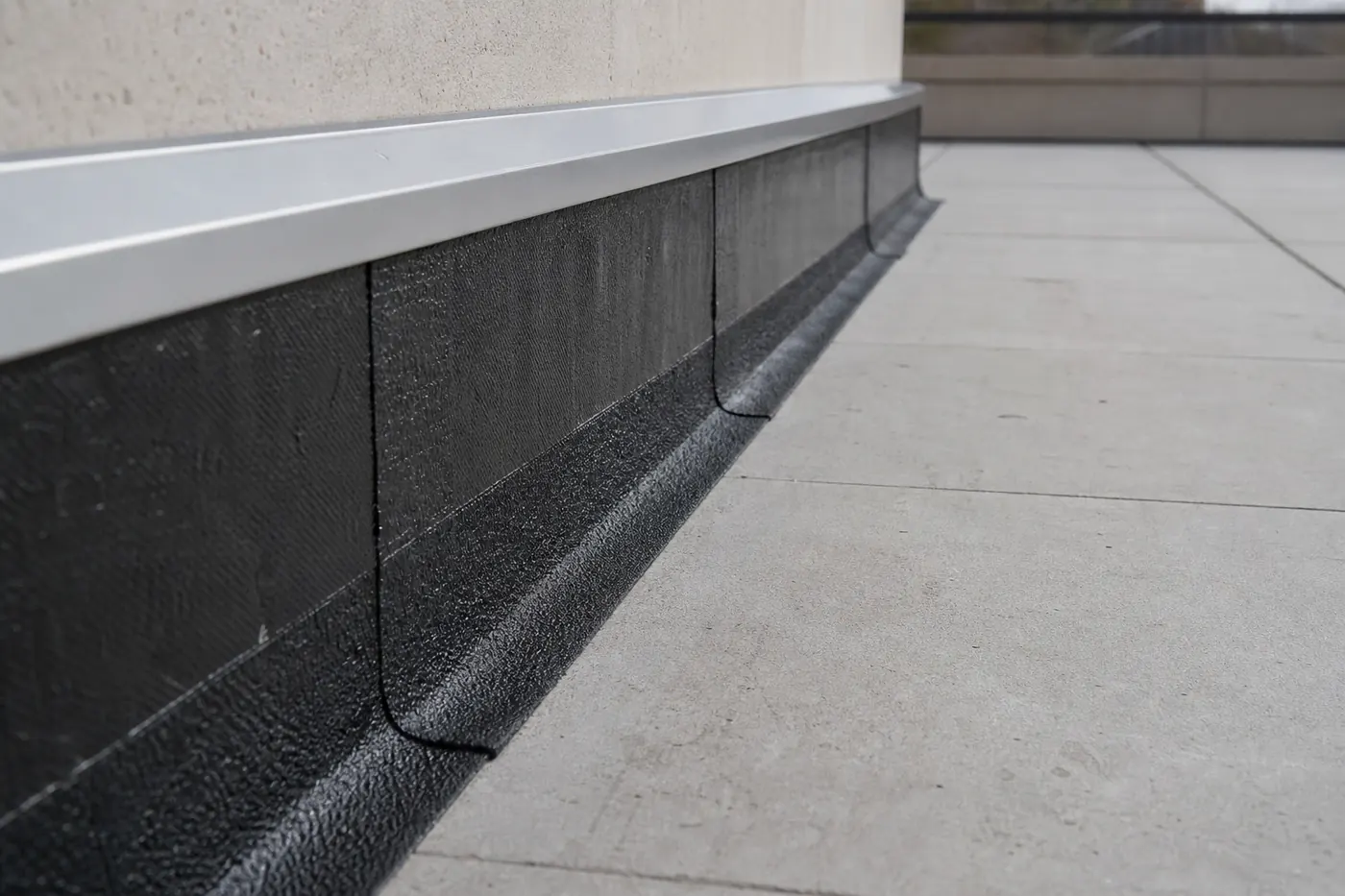 Relevé d’étanchéité en pied de mur sur une terrasse, membrane bitumineuse remontée sous un solin métallique