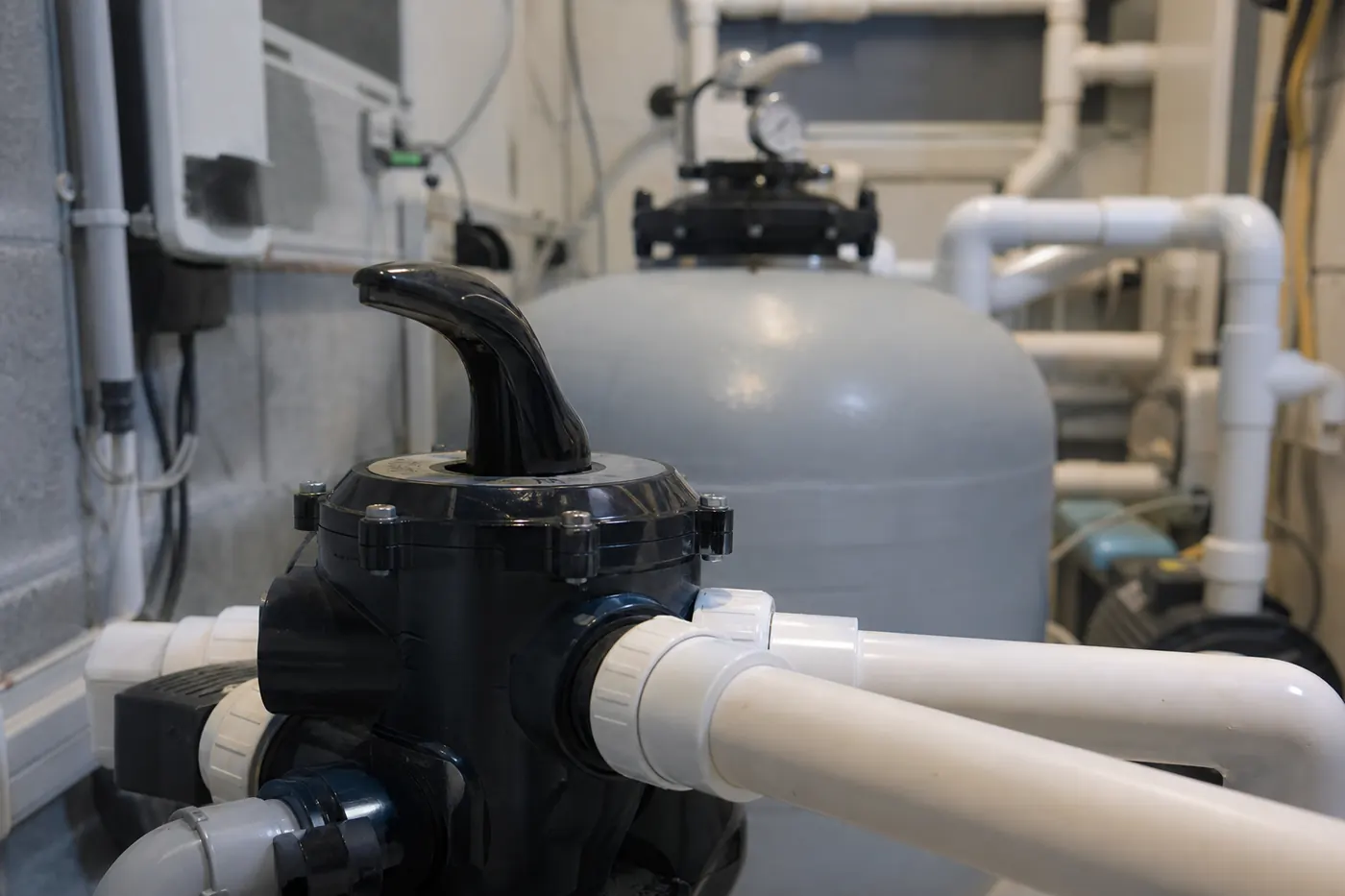 Local technique de piscine, filtre à sable, pompe et jeu de vannes multivoies sur canalisations PVC